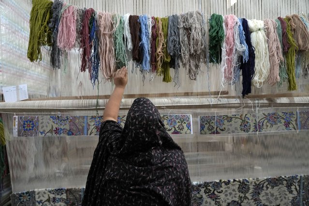 An Iranian woman weaves a carpet at a workshop in the city of Kashan, about 152 miles (245 km) south of the capital Tehran, Iran, Tuesday, April 30, 2024. (Photo by Vahid Salemi/AP Photo)