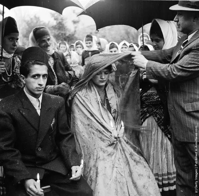 1952:  A Khan or feudal lord of a province lifts the veil from the face of a muslim bride in a village wedding ceremony. Her groom sits beside her with lit candles symbolising life