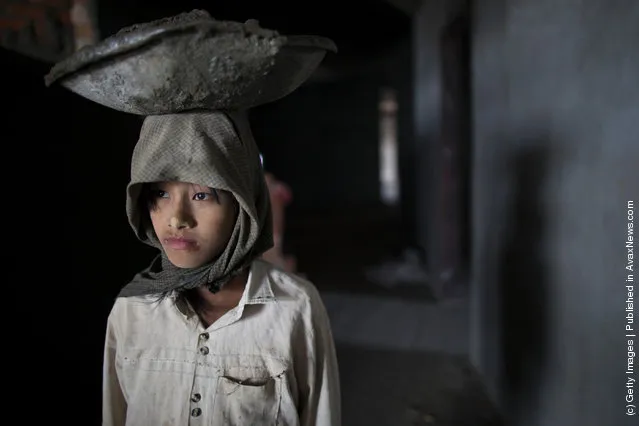 A Burmese girl carries cement on her head as she works at a construction site for a new hotel