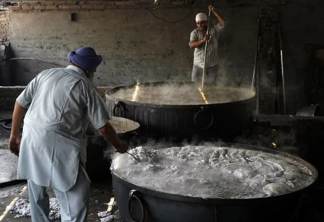 Workers cook food to be distributed at a langar (community kitchen) in the premises of Golden temple, the holiest Sikh shrine, in Amritsar May 8, 2010. (Photo by Yasir Iqbal/Reuters)