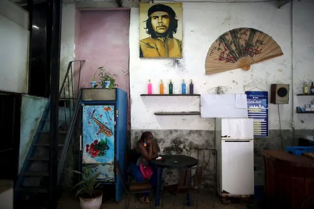 A woman sits under an image of late revolutionary hero Ernesto “Che” Guevara inside a state-run bar in Havana, Cuba, April 19, 2016. (Photo by Alexandre Meneghini/Reuters)
