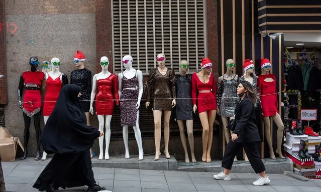 Going right a pedestrian wearing a full black haji walks past mannequins as all in black lady wearing contemporary fashion passes going ot left in Istanbul, Turkey on December 30, 2021. As all kinds of people shop for pre-New Year celebration preparations at Mahmutpasali Bazaar in Eminonu. (Photo by Tolga Ildun/ZUMA Press Wire/Rex Features/Shutterstock)