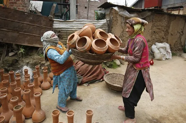A Kashmiri woman puts pottery items into a basket and passes it to another family member before putting it for sale in the market on the outskirts of Srinagar, the summer capital of Indian Kashmir, India, 03 May 2016. According to these potters, their entire family gets involved in the trade and ends up earning only around eight Euros per day while their next generations are mostly not keen to continue with the business as most people no longer prefer pottery items due to the lifestyle changes and use of modern utensils. (Photo by Farooq Khan/EPA)