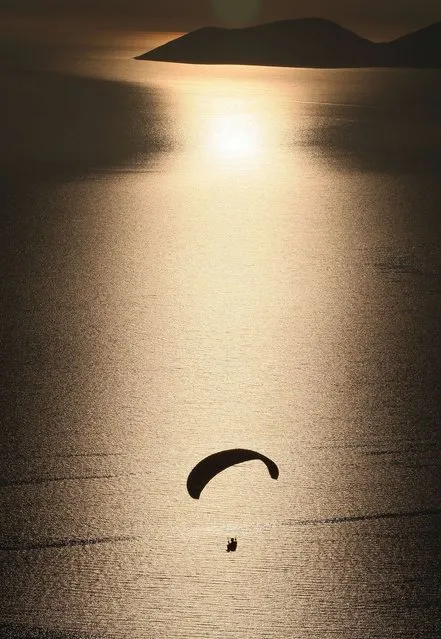 A paraglider flies over the sea close to the Albanian coastal town of Vlora on May 7, 2014, as part of the Paragliding Albania Open 2014. (Photo by Gent Shkullaku/AFP Photo)