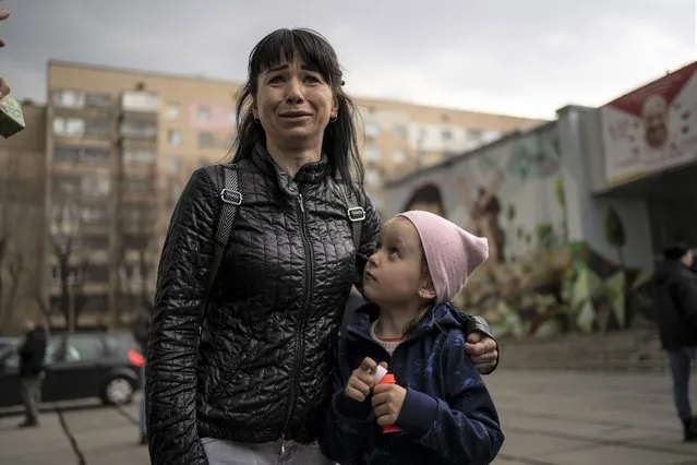 Julia, 34 , cries next to her daughter Veronika, 6, while talking to the press in Brovary, on the outskirts of Kyiv, Ukraine, Tuesday, March 29, 2022. (Photo by Rodrigo Abd/AP Photo)