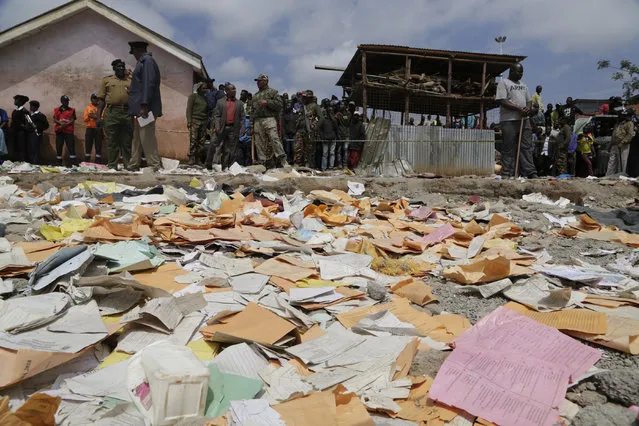 School papers lie on the ground as people gather at the site of the Precious Talent Top School building after it collapsed in Nairobi, Kenya, Monday, September 23, 2019. A school collapsed in Kenya's capital on Monday and killed at least seven children, officials said, while some outraged residents alleged shoddy construction.(Photo by Khalil Senosi/AP Photo)