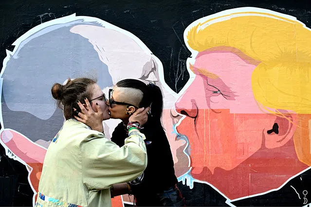 Two women kiss in front of mural depicting Russian President Vladimir Putin, left, and Republican presidential candidate Donald Trump, on the walls of a barbecue bar “Keule Ruke” in the old town in Vilnius, Lithuania, Thursday, 19 May, 2016. The mural, unveiled last week, was painted by local artist Mindaugas Bonanu. People – straight and gay – flocked to have recreate the image and have their photos taken in front of it. (Photo by Splash News and Pictures)