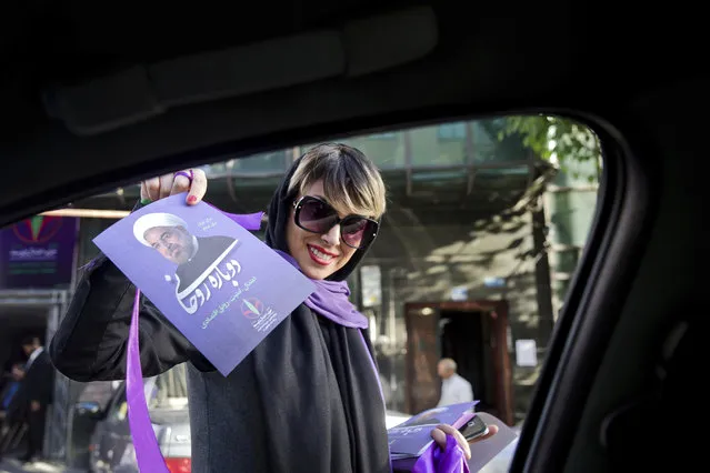 In this Wednesday, May 10, 2017 photo, a supporter of Iranian President Hassan Rouhani hands out his posters for May 19 presidential election in downtown Tehran, Iran. Who wins Iran's upcoming presidential election likely will turn on turnout. Historically, the more Iranians who cast ballots, the greater the chance a reformist or a moderate like incumbent President Hassan Rouhani will be elected. (Photo by Ebrahim Noroozi/AP Photo)