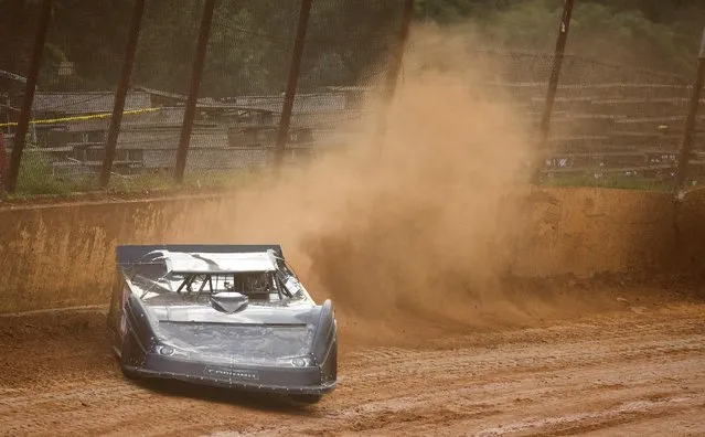 In this July 17, 2015 photo, a driver in a late model race car kicks up a cloud of orange clay dirt as he takes a turn at the Ponderosa Speedway in Junction City, Ky. At the Ponderosa Speedway, a race track made of red clay and nestled in the small hills of central Kentucky, spectators can be sure they will take a little piece of the track with them at the end of the night. (Photo by David Stephenson/AP Photo)
