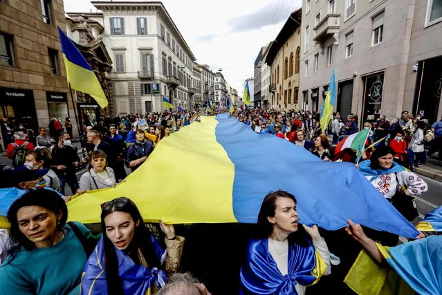 People carry a huge Ukrainian flag as they attend a rally on the occasion of the 77th anniversary of Liberation Day in Milan, Italy, 25 April 2022. Liberation Day (Festa della Liberazione) is a nationwide public holiday in Italy that is annually celebrated on 25 April. The day remembers Italians who fought against the Nazis and Mussolini's troops during World War II and honors those who served in the Italian Resistance. (Photo by Mourad Balti Touati/EPA/EFE)