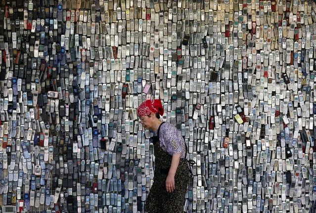 A woman walks past a wall of mock-up mobile phones displayed outside an electronics store in downtown Tokyo, Japan, Thursday, June 2, 2016. The store owner started this display with a few thousands of cellphones ten years ago, which continue to draw attention from those who pass by. (Photo by Shuji Kajiyama/AP Photo)