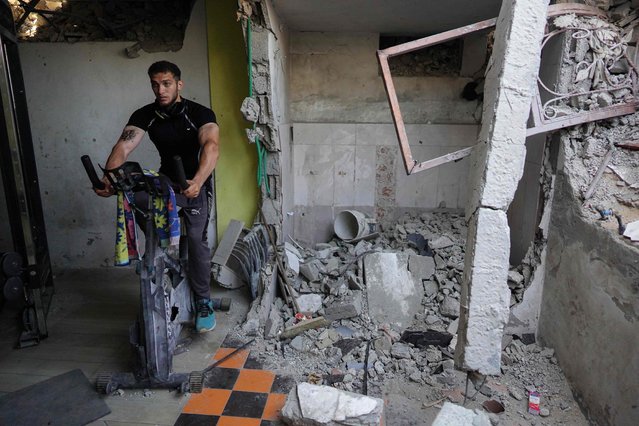 A Palestinian man trains on a stationary bike at a damaged gym, which was recently re-opened in Khan Yunis in the southern Gaza Strip on August 7, 2024 amid the ongoing conflict between Israel and the Palestinian Hamas militant group. (Photo by Bashar Taleb/AFP Photo)