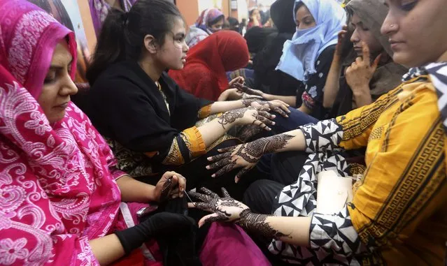 Pakistani beauticians paint hands of customers with traditional henna in preparation for the upcoming Eid al-Fitr holidays, that marks the end of the holy fasting month of Ramadan, at a beauty saloon in Karachi, Pakistan, Monday, May 2, 2022. (Photo by Fareed Khan/AP Photo)