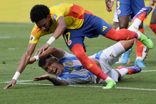 Colombia's Johan Mojica falls over Argentina's Lisandro Martinez during a qualifying soccer match for the FIFA World Cup 2026 at the Metropolitano Roberto Melendez stadium in Barranquilla, Colombia, Tuesday, September 10, 2024. (Photo by Ricardo Mazalan/AP Photo)