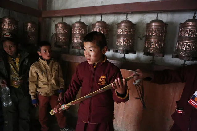 A young monk holds a ceremonial sword for a dancer before a ritual during the Tenchi Festival on May 26, 2014 in Lo Manthang, Nepal. The Tenchi Festival takes place annually in Lo Manthang, the capital of Upper Mustang and the former Tibetan Kingdom of Lo. Each spring, monks perform ceremonies, rites, and dances during the Tenchi Festival to dispel evils and demons from the former kingdom. (Photo by Taylor Weidman/Getty Images)