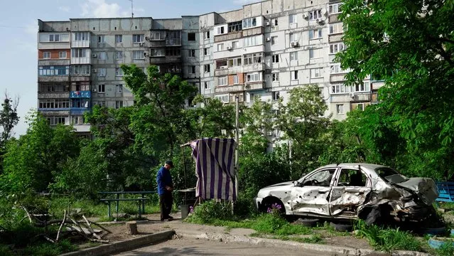 A man stands in a yard in front of a damaged residential building in Mariupol on May 31, 2022, amid the ongoing military action in Ukraine. (Photo by AFP Photo/Stringer)