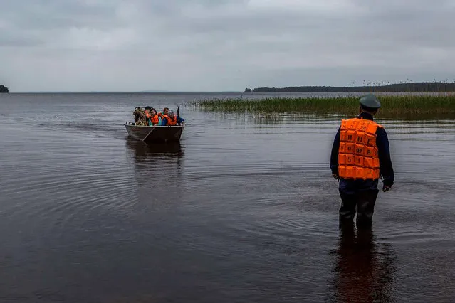Emergency officers carry surviving children in a boat on Lake Syamozero in Russia's autonomic republic of Korelia on June 19, 2016. At least 14 children on a summer camp in northeast Russia drowned when their boats capsized in a storm on the lake, investigators said Sunday. The accident happened overnight on Lake Syamozero, close to the border with Finland, according to Vladimir Markin, a spokesman for Russia's investigative committee. The emergencies ministry said the children were sailing on two boats and a raft when they got caught in a storm after nightfall. Rescuers saved around 30 people, the ministry told RIA Novosti. (Photo by AFP Photo/Stringer)