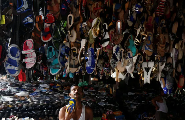 A shopkeeper hangs footwear at his road side footwear stall under a flyover in Kolkata, India, July 12, 2017. (Photo by Rupak De Chowdhuri/Reuters)