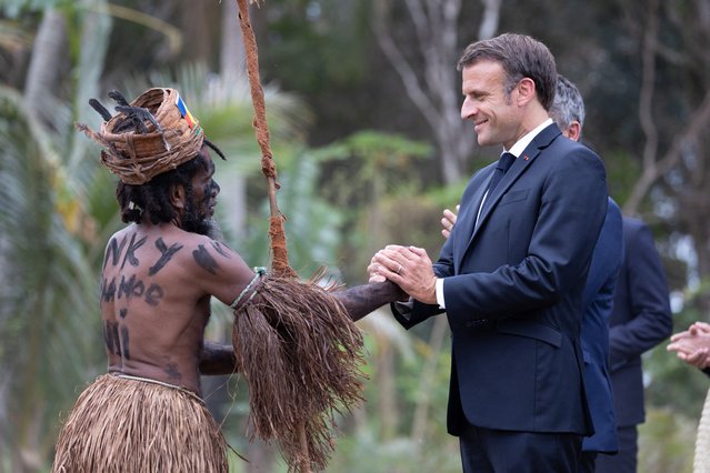 French President Emmanuel Macron shakes hands with a traditional dancer during a customary ceremony in his honour in Touho, north of New Caledonia on July 25, 2023. (Photo by Raphael Lafargue/Pool via AFP Photo)