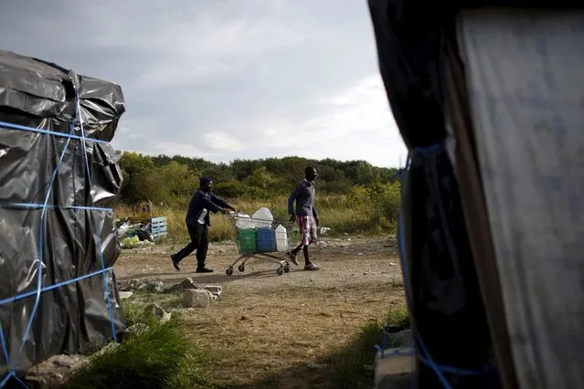 Two African migrants use a shopping cart to transport water at “The New Jungle” camp in Calais, France, August 8, 2015. (Photo by Juan Medina/Reuters)