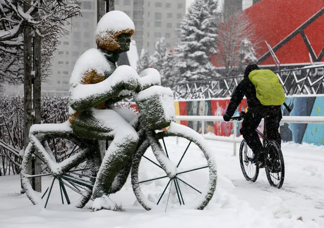 A bicycle rider passes by a street installation during snowfall in Stavropol, Russia on January 31, 2020. (Photo by Eduard Korniyenko/Reuters)
