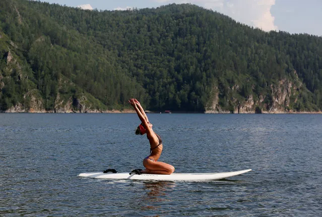 Yulia Boyarintseva, a master of snow boarding and snow kiting sports, practices Float Board Yoga on the Yenisei River on a hot summer day, with the air temperature at about 32 degrees Celsius (89.6 degrees Fahrenheit), as she rests in a summer camp outside the Siberian city of Krasnoyarsk, Russia, August 4, 2017. (Photo by Ilya Naymushin/Reuters)