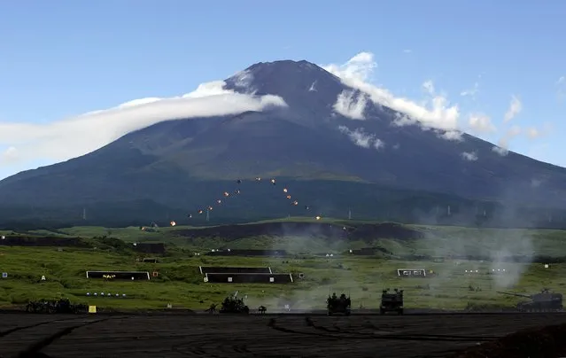 Japanese Ground Self-Defense Force armoured vehicles fire missiles to form a shape of Mount Fuji, seen in the background, as part of a skills display during an annual training session, which is based on a scenario to defend or retake islands in Japanese territory, at Higashifuji training field in Gotemba, west of Tokyo, August 18, 2015. (Photo by Yuya Shino/Reuters)