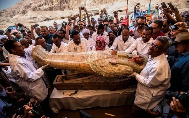 Egyptian archeologist open a wooden coffin belonging to a man in front Hatshepsut Temple at Valley of the Kings in Luxor on October 19, 2019. Egypt revealed on Saturday a rare trove of 30 ancient wooden coffins that have been well-preserved over millennia in the archaeologically rich Valley of the Kings in Luxor. (Photo by Khaled Desouki/AFP Photo)