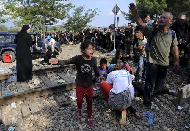 People react as they are held back by police at the border line dividing Macedonia and Greece August 21, 2015. (Photo by Ognen Teofilovski/Reuters)