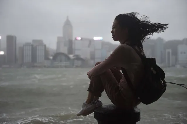 A woman looks out to Victoria Harbour during heavy winds and rain brought on by Typhoon Hato in Hong Kong on August 23, 2017. Typhoon Hato smashed into Hong Kong on August 23 with hurricane force winds and heavy rains in the worst storm the city has seen for five years, shutting down the stock market and forcing the cancellation of hundreds of flights. (Photo by Anthony Wallace/AFP Photo)