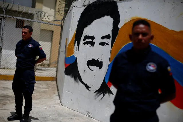 Security guards stand in front of a mural depicting Venezuela's President Nicolas Maduro during a visit of representatives of Mercosur in the Rodeo III prison in Guatire, Venezuela July 1, 2016. (Photo by Carlos Garcia Rawlins/Reuters)