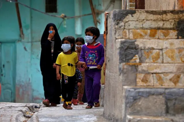 Iraqi children wear protective masks as they walk near a religious school where the first coronavirus case was detected, following the outbreak of the coronavirus, in the holy city of Najaf, Iraq, February 24, 2020. (Photo by Alaa al-Marjani/Reuters)