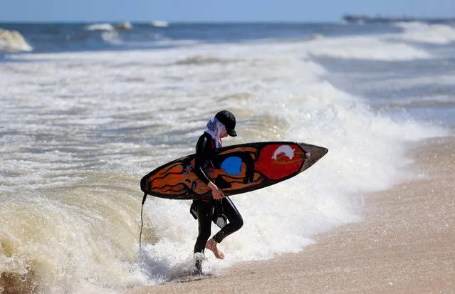 Sabah Abu Ghanem, a 22-year-old Palestinian surfer, is pictured with a surf board off the shore of Gaza City, on June 13, 2022. Palestinians in the Israeli-blockaded Gaza Strip are rediscovering the pleasure of the sea, after authorities declared the end of a long period of hazardous marine pollution. Six months ago, a German-funded plant began operating in central Gaza, and now treats 60,000 cubic metres of wastewater per day, which is half the enclave's sewage, according to an official at Gaza's environment ministry. (Photo by Mohammed Abed/AFP Photo)