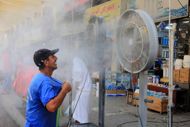 An Iraqi man cool himself off in a spray of water during a sweltering hot day at the Al-Khilani square in central Baghdad, Iraq, 19 July 2022. Baghdad suffers a heatwave as temperatures rose to more than 50 degrees Celsius, amid an acute shortage of electricity. (Photo by Ahmed Jalil/EPA/EFE)