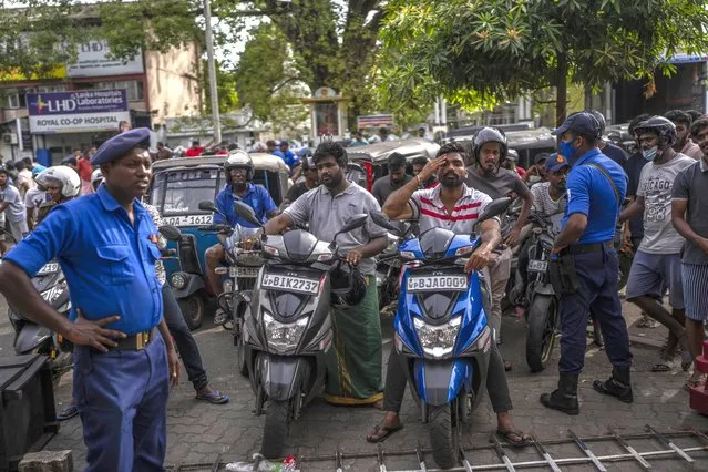 Police officers stand guard as people wait in queue to buy petrol at a fuel station, in Colombo, Sri Lanka, July 17, 2022. Bankruptcy has forced the island nation's government to a near standstill. Parliament is expected to elect a new leader Wednesday, paving the way for a fresh government, but it is unclear if that's enough to fix a shattered economy and placate a furious nation of 22 million that has grown disillusioned with politicians of all stripes. (Photo by Rafiq Maqbool/AP Photo)