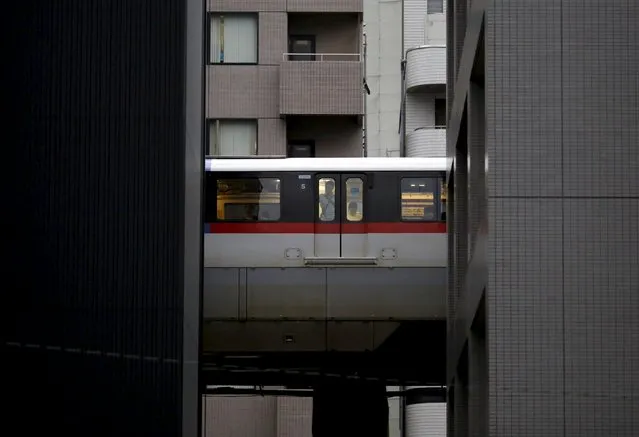 A man looks through a window of a monorail as it travels past office buildings in Tokyo August 26, 2015. (Photo by Toru Hanai/Reuters)