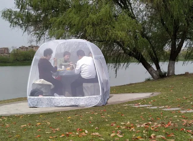 People enjoy a meal inside a tent to prevent the coronavirus at a park in Nanjing, Jiangsu province, China on March 24, 2020. (Photo by China Daily via Reuters)