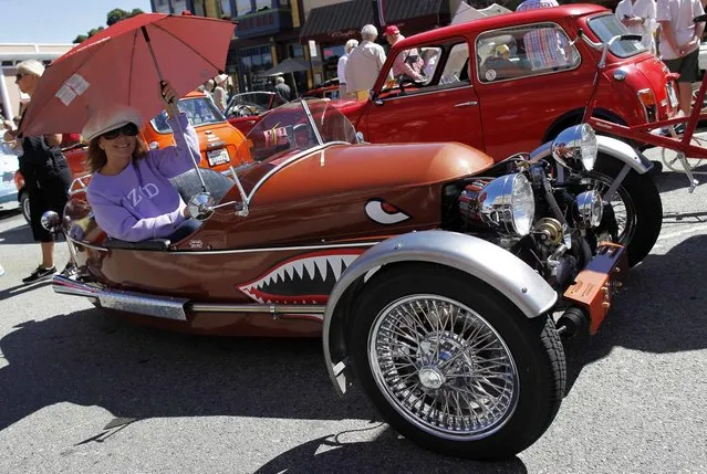 Diana Giffin poses with her replica of a 1937 Morgan 3-wheeler during the Little Car Show in Pacific Grove, California, August 13, 2014. The event, which showcases small cars with up to 1,601cc engines as well as electric cars, is held during the Pebble Beach Automotive Week which culminates with the Concours d'Elegance. (Photo by Michael Fiala/Reuters)