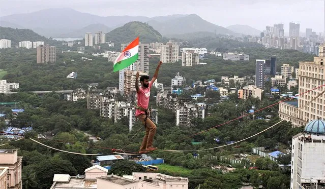 Harsdeep Powar from Team Slackistan walks a rope, holding the flag of India to celebrate the country's 75th Independence Day in Mumbai, India on August 15, 2022. (Photo by Francis Mascarenhas/Reuters)
