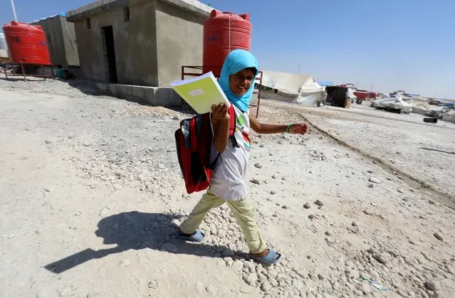 A displaced child from the Islamic State (IS) group's Syrian stronghold of Raqa, walks to attend the first day of the new school year at a camp for internally displaced people in Ain Issa on August 22, 2017. (Photo by Delil Souleiman/AFP Photo)