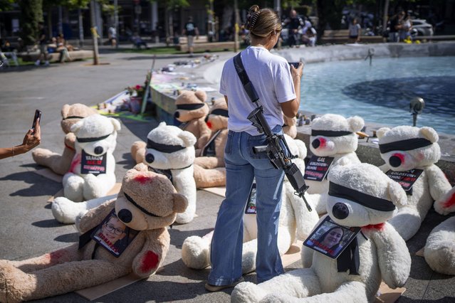 An off-duty Israeli soldier takes photos of an installation of blindfolded giant teddy bears adorned with photos of Israelis held captive in Gaza, in Tel Aviv, Israel, Wednesday, October 25, 2023. The installation is meant to draw attention to over 200 people who were abducted by Hamas militants during a bloody and unprecedented Oct. 7 cross-border attack. (Photo by Oded Balilty/AP Photo)