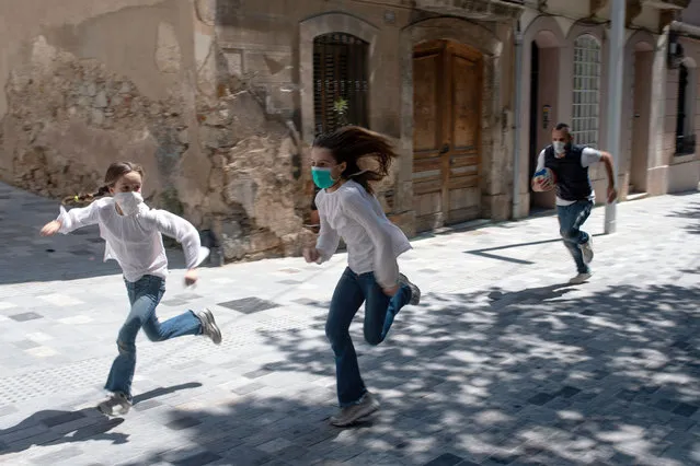 Joan, 45, chases his daughters Ines, 11, and Mar, 9, as they play in the street on April 26, 2020, in Barcelona, during a national lockdown to prevent the spread of the COVID-19 disease. After six weeks stuck at home, Spain's children were being allowed out today to run, play or go for a walk as the government eased one of the world's toughest coronavirus lockdowns. Spain is one of the hardest hit countries, with a death toll running a more than 23,000 to put it behind only the United States and Italy despite stringent restrictions imposed from March 14, including keeping all children indoors. (Photo by Josep Lago/AFP Photo)
