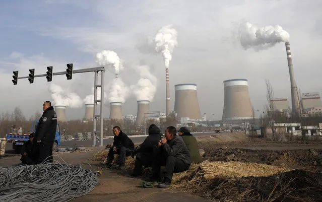 In this December 3, 2009 file photo, Chinese workers take a break in front of the cooling towers of a coal-fired power plant in Dadong, Shanxi province, China. (Photo by Andy Wong/AP Photo)