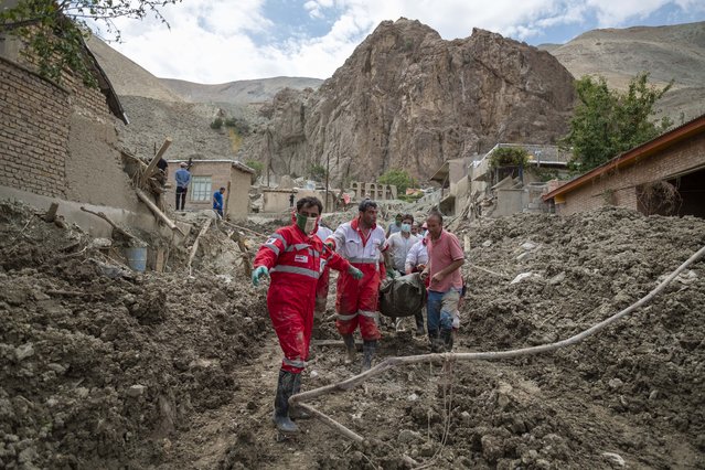 Members of the Iranian Red Crescent Society (IRCC) and villagers carrying a body found from the ruins of a destroyed house in the flooded village of Mazdaran in Firoozkooh county 124 km (77 miles) northeast of Tehran, after flash flooding, July 31, 2022. (Photo by Morteza Nikoubazl/NurPhoto via Getty Images)