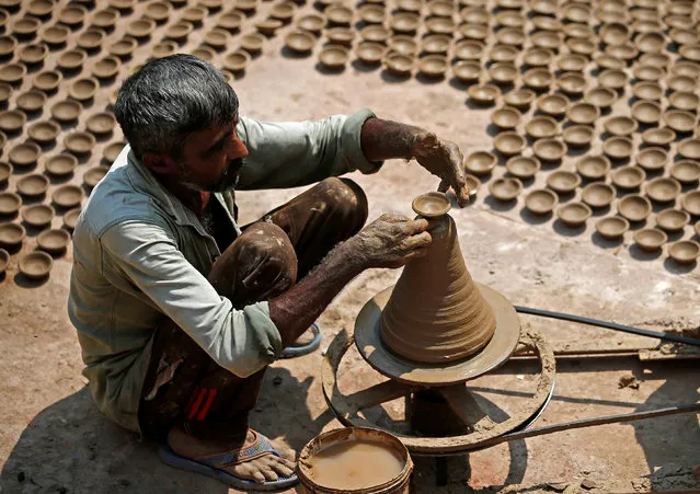 A man makes earthen lamps which are used to decorate temples and homes during the Hindu festival of Diwali, at a workshop in Ahmedabad, India October 10, 2017. (Photo by Amit Dave/Reuters)