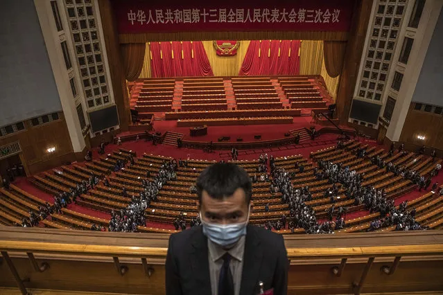A security official wearing a protective face mask stands guard as delegates leave after the second plenary session of China's National People's Congress (NPC) at the Great Hall of the People in Beijing, Monday, May 25, 2020. (Photo by Roman Pilipey/Pool Photo via AP Photo)