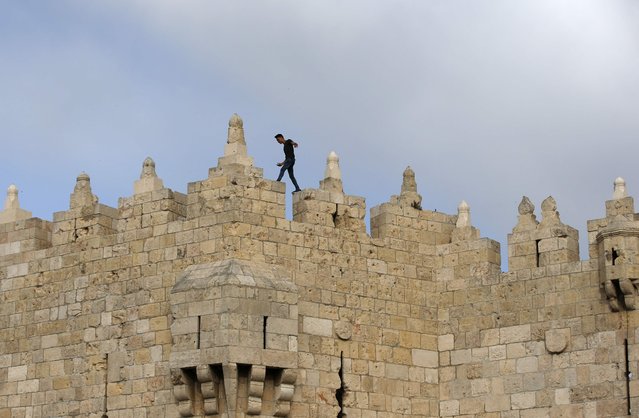A Palestinian youth walks on top of the Damascus Gate building in Jerusalem's Old City on May 18, 2017. (Photo by Ahmad Gharabli/AFP Photo)