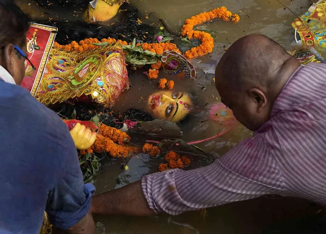 Devotees immerse an idol of Hindu Goddess Durga in a makeshift pond at a park on the last day of Durga Puja festival in New Delhi, Wednesday, October 5, 2022. (Photo by Manish Swarup/AP Photo)