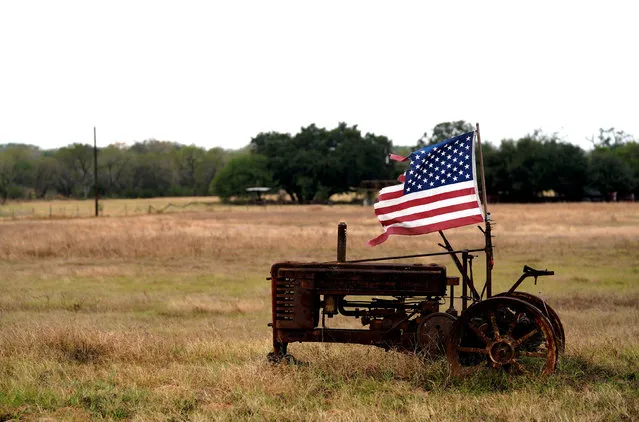 A tattered U.S. flag flies on an old tractor in a farm field outside Sutherland Springs, near the site of the shooting at the First Baptist Church of Sutherland Springs,Texas, U.S. November 8, 2017. (Photo by Rick Wilking/Reuters)