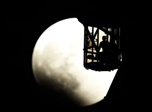 The Earth's shadow renders the moon as a couple in Ferris wheel observe it during a total lunar eclipse in Tokyo, Wednesday, October 8, 2014. (Photo by Koji Sasahara/AP Photo)